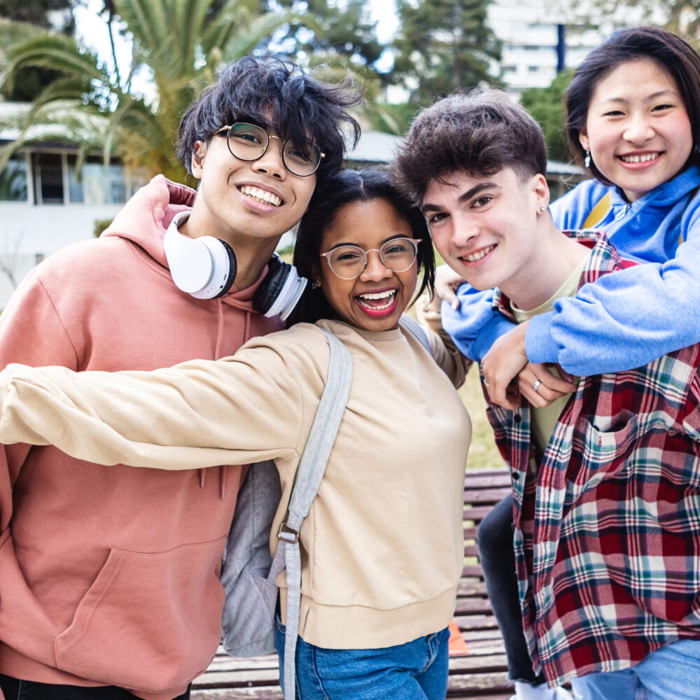 Cheerful multiracial group of young students friends smiling at camera while standing outdoors at campus university - Education and millennial people concept